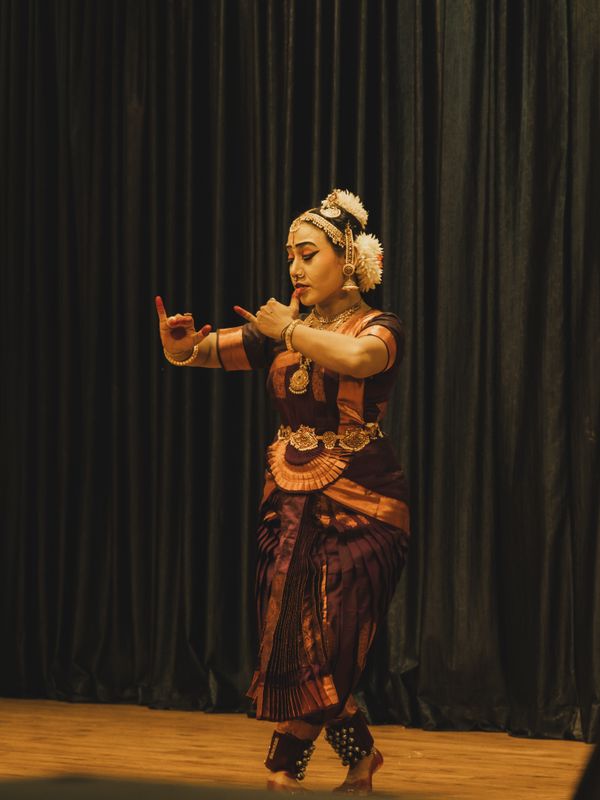 A classical dancer performing on a dark stage