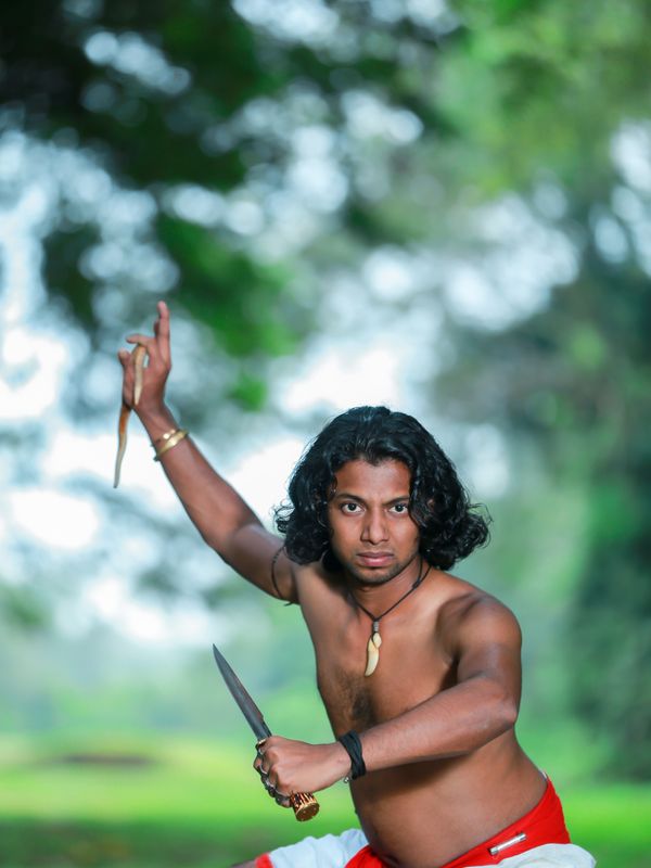 A warrior in a dhoti striking a martial pose with a dagger
